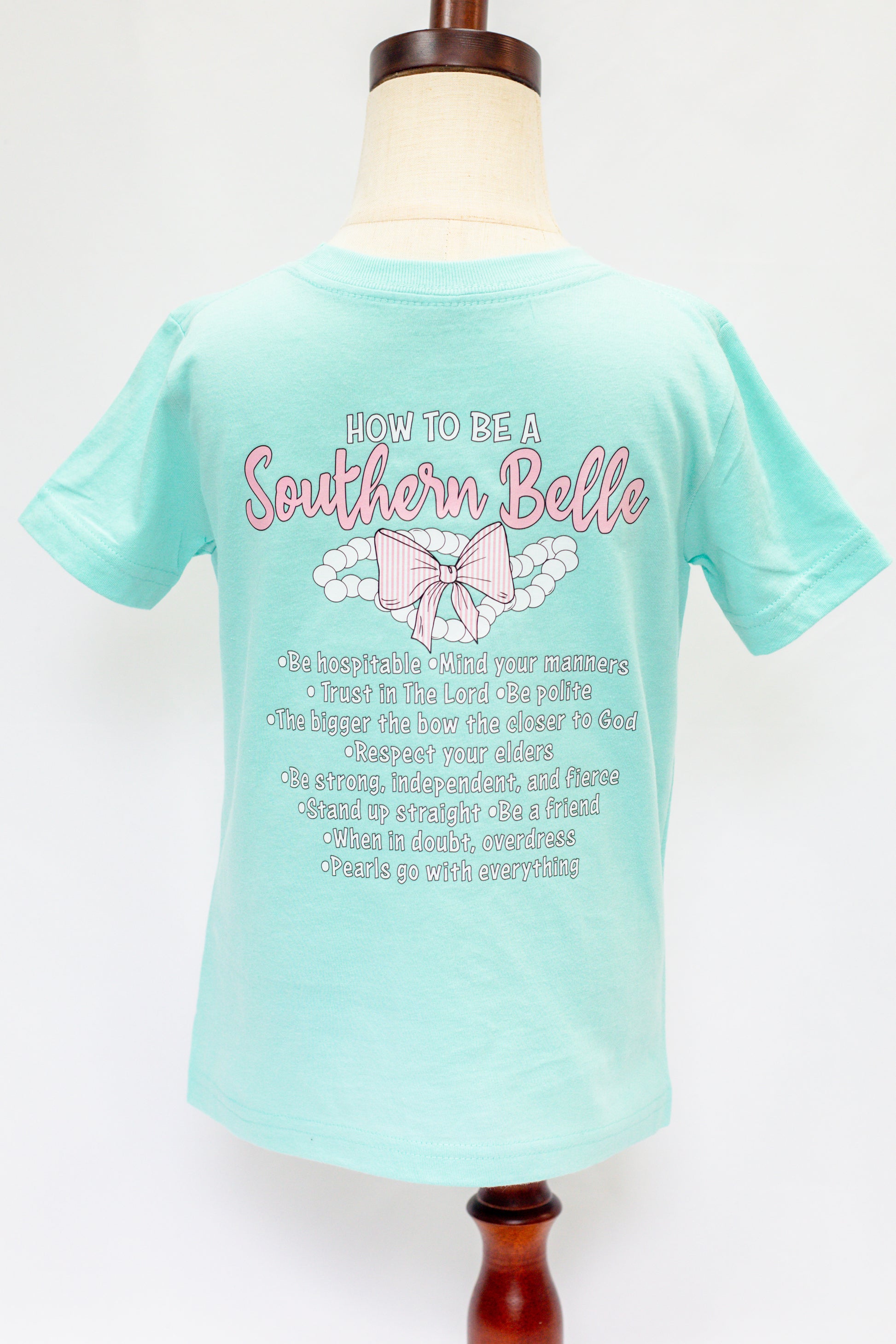 Mint green t-shirt with 'How to be a Southern Belle' text and graphics on a mannequin against a white background
